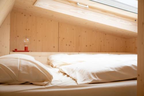 a bed with two pillows and a window on it at Tiny House Pioneer 18 Zur Meerseite - Green Tiny Village Harlesiel in Carolinensiel