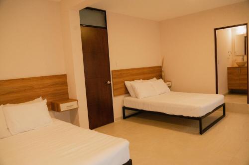 a hotel room with two beds and a mirror at Hotel Fratelli in Aguascalientes