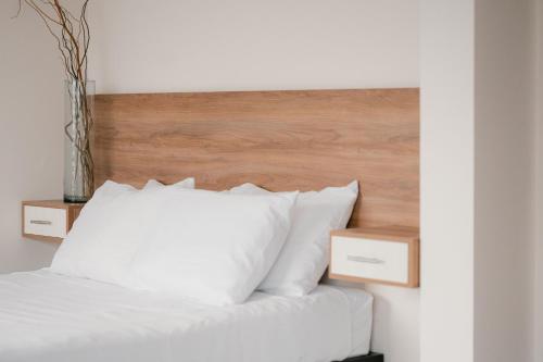 a white bed with a wooden headboard and white pillows at Hotel Fratelli in Aguascalientes