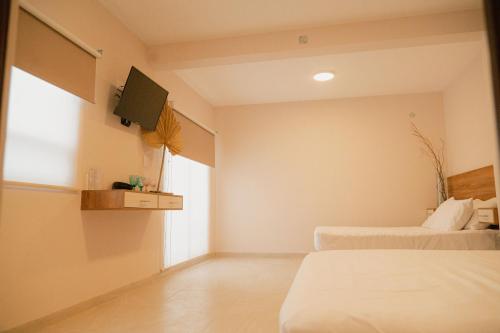 a bedroom with two beds and a tv on the wall at Hotel Fratelli in Aguascalientes