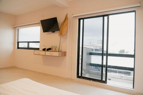 a bedroom with a large window and a tv at Hotel Fratelli in Aguascalientes