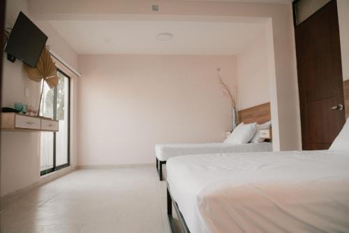a bedroom with two beds and a window at Hotel Fratelli in Aguascalientes