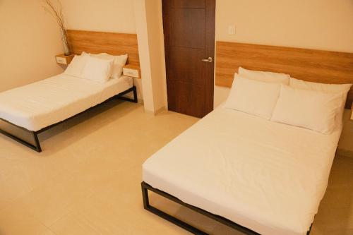 a bedroom with two beds with white sheets and pillows at Hotel Fratelli in Aguascalientes