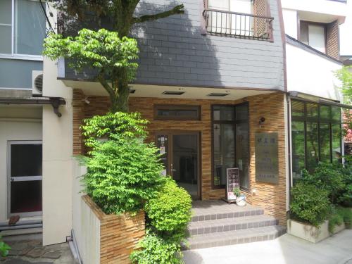 un edificio con un árbol delante de él en Hakone Miyanoshita Myojokan en Hakone