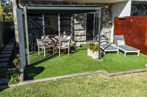 a patio with a table and chairs on the grass at Dolphin Shores in Corlette