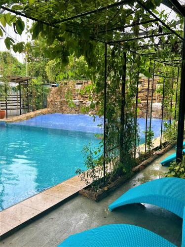 a large swimming pool with blue water and trees at Casa Cecilia Hotel in Bantay