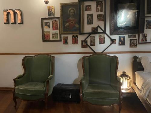 two green chairs in a room with a bed and pictures at 103 - Bed and Brews in Bangkok