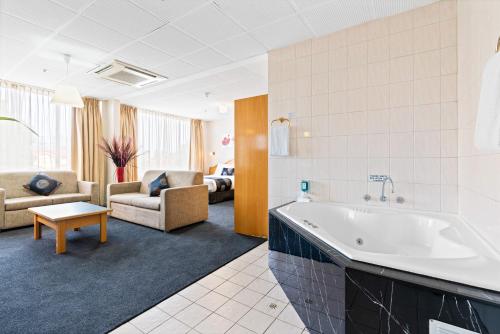a large bathroom with a tub and a living room at Adelaide International Motel in Adelaide