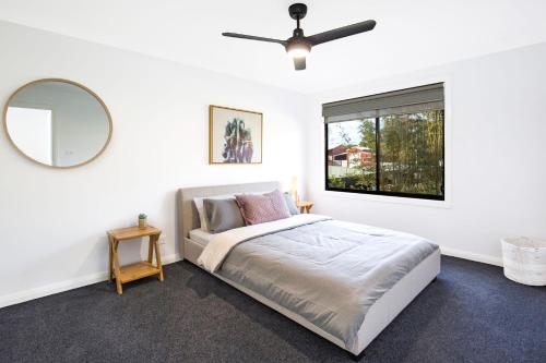カルバーラ・ビーチにあるGumnut Pet Friendly 5 Mins Walk to Beachのベッドルーム1室(鏡付きのベッド1台、窓付)