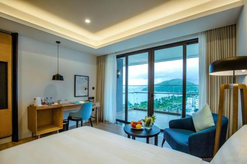 a hotel room with a bed and a desk and a large window at FLC City Hotel Beach Quy Nhon in Quy Nhon