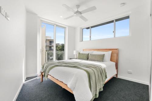 a white bedroom with a bed and windows at Kings Surf Unit 6 5 Ormonde Tce Kings Beach in Caloundra