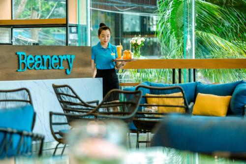 a woman standing in a restaurant with a table and chairs at FLC City Hotel Beach Quy Nhon in Quy Nhon