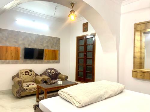 a bedroom with a bed and a couch and a table at Hotel Swagatam in Bikaner