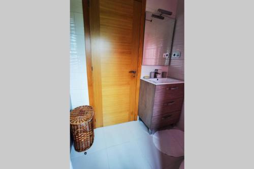 baño pequeño con lavabo y puerta de madera en Foz Acogedora casa familiar, en Barrosa