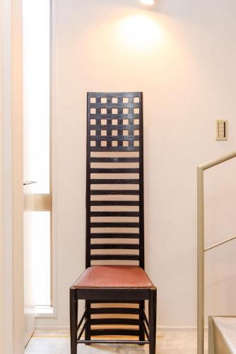 a wooden chair sitting next to a wall at vacation rental SARAKU 茶楽来 in Osaka