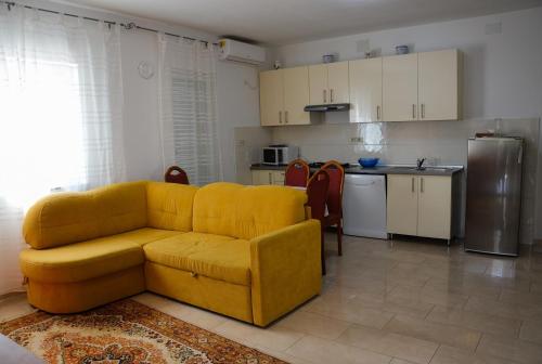 a living room with a yellow couch and a kitchen at Apartman Zrina Oštro in Kraljevica