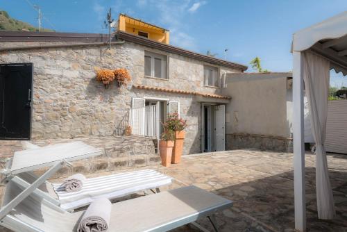 een stenen huis met twee banken ervoor bij Casa delle sirene in Letojanni