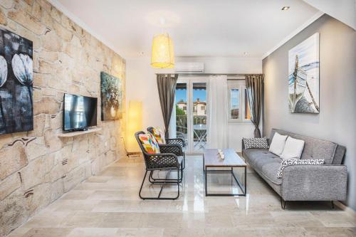 a living room with a couch and chairs and a tv at Boutique Maisonette in Pefkohori