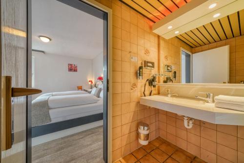 a bathroom with a sink and a bed in a room at Hotel Seeblick Försterhaus in Owschlag