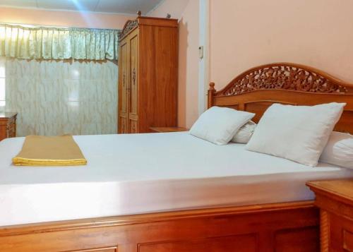 a bedroom with a large wooden bed with white pillows at Hotel Mario Pulana Bone in Watampone