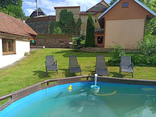 a swimming pool in a yard with two chairs at Chaloupka u Vejvodů in Skřípov