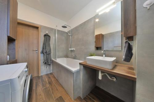 a bathroom with a sink and a tub and a mirror at Veľký 2i byt pri Opere v priamom centre Banskej Bystrice in Banská Bystrica