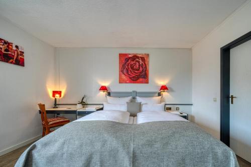 a bedroom with a large bed and a desk at Hotel Seeblick Försterhaus in Owschlag