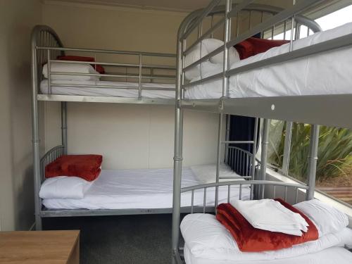 a room with three bunk beds with white sheets at All Seasons Holiday Park in Rotorua