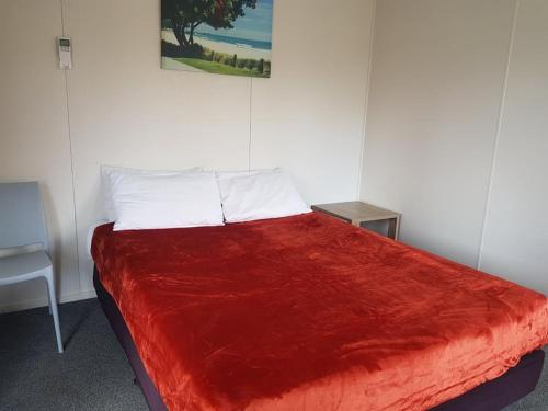 uma cama num quarto com um cobertor vermelho em All Seasons Holiday Park em Rotorua