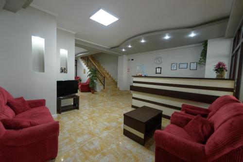 une salle d'attente avec des chaises rouges et une télévision dans l'établissement Hotel Cora, à Constanţa