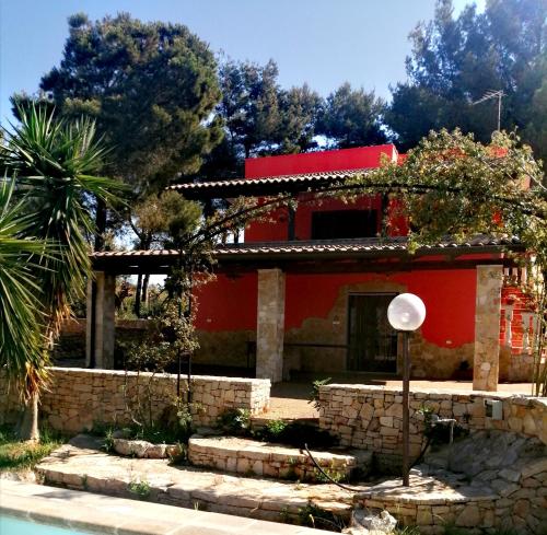 une maison rouge avec une piscine en face de celle-ci dans l'établissement Villetta In Campagna, à Parabita