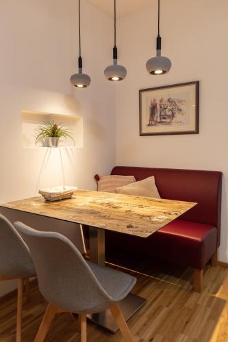 a dining room with a wooden table and a red couch at Pannonia Appartements 2 in Neusiedl am See