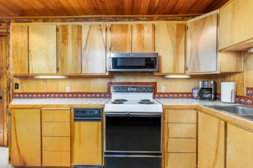 a kitchen with a stove and a microwave at Alpine Meadows Log Cabin in Girdwood
