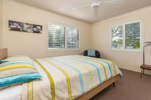 a bedroom with a bed and two windows at Seahorse 4 in Tuncurry