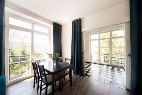 a dining room with a table and chairs and large windows at L.E. Home II in Leipzig