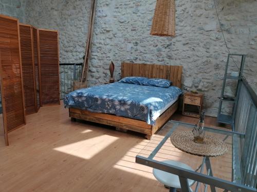 a bedroom with a bed and a table in a room at LE LOFT in Casteljaloux