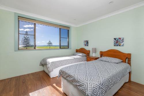 two beds in a room with a window at Surfspray 3 Pebbly Beach in Forster