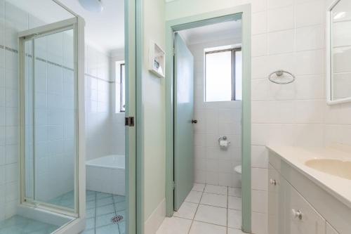 a white bathroom with a shower and a sink at Surfspray 3 Pebbly Beach in Forster