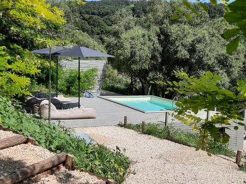 una piscina con sombrilla junto a una terraza en Tuffudesu Experience, en Osilo