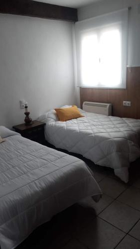 two beds in a hotel room with a window at Casa Flor in Arcas