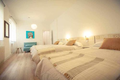 1 Schlafzimmer mit 3 Betten und einem blauen Stuhl in der Unterkunft Guardaviñas62 in Logroño