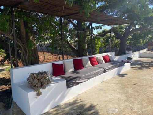 a white couch with red pillows sitting under a canopy at Trulli Demetra in Martina Franca