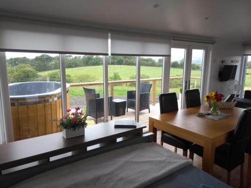 a dining room with a table and a view of a tub at Cleeves Cabins Ailsa Luxury Lodge with hot tub in Dalry
