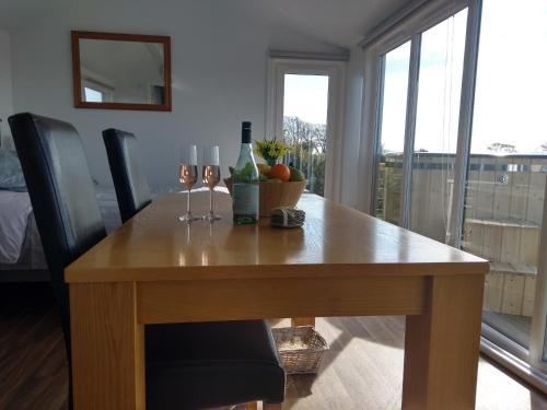 a wooden table with two wine glasses on top of it at Cleeves Cabins Ailsa Luxury Lodge with hot tub in Dalry