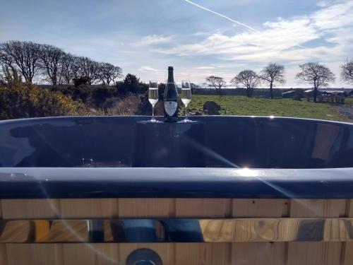 a blue bath tub with a bottle of wine in it at Cleeves Cabins Ailsa Lodge with hot tub luxury in Dalry