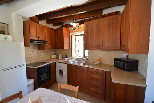 a kitchen with wooden cabinets and a sink and a dishwasher at Elpida's Stone Houses in Goudhi