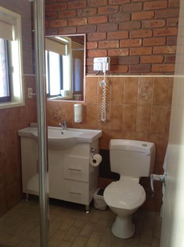 a bathroom with a toilet and a sink and a mirror at Melton Motor Inn and Apartments in Melton