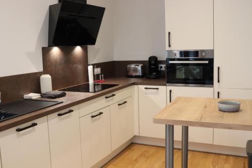 une cuisine avec des armoires blanches et une table en bois dans l'établissement Le Mans Hypercentre - proche place République, au Mans