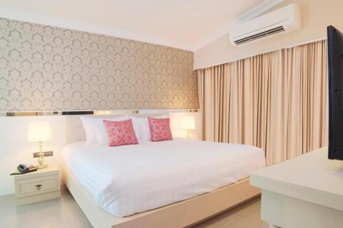 a bedroom with a white bed with pink pillows at The Raya Surawong Bangkok in Bangkok