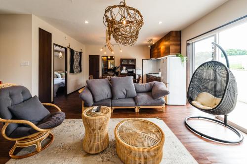 a living room with a couch and chairs and a fan at BB Wakugawa Terrace in Nakijin